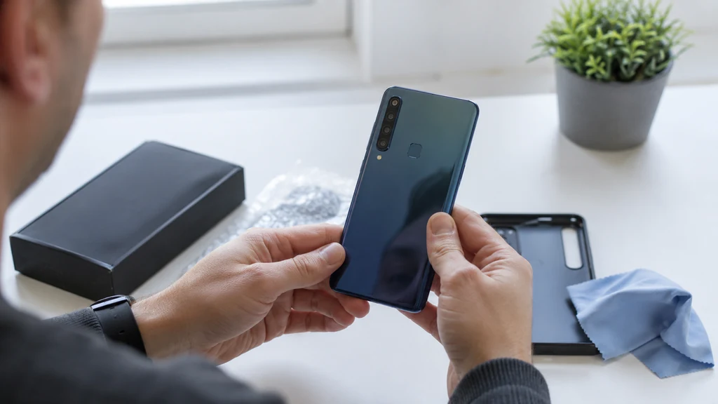 Acheteur inspectant un Samsung Galaxy A9 Phone d’occasion avec son quadruple capteur photo